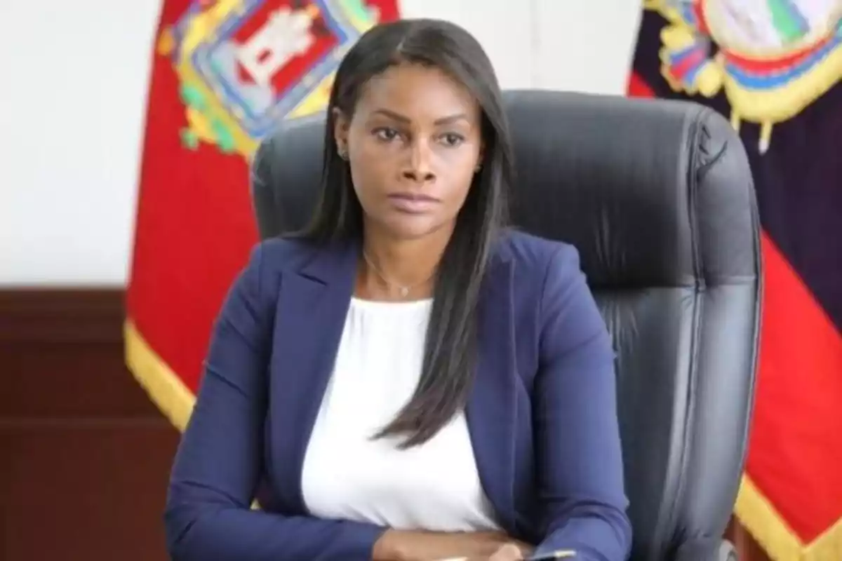 A woman sitting in an office chair with flags in the background.