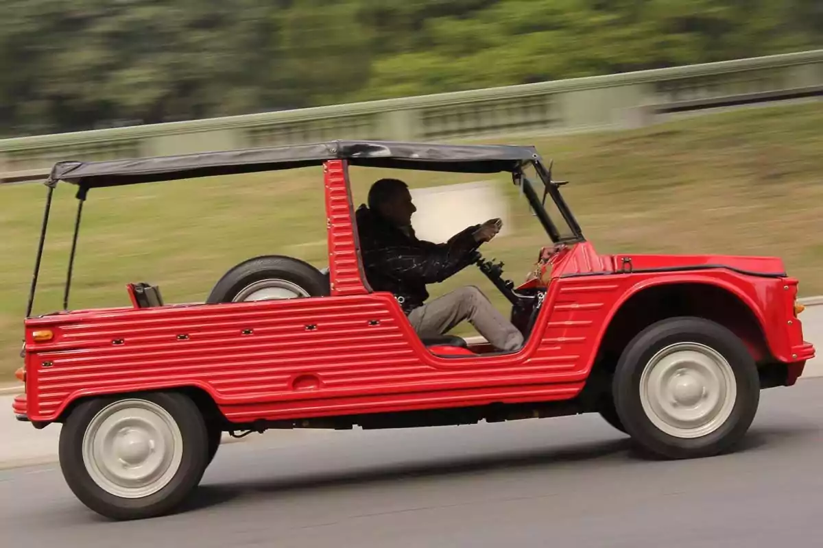 A man driving a red classic convertible car in motion. A man driving a red classic convertible car in motion.