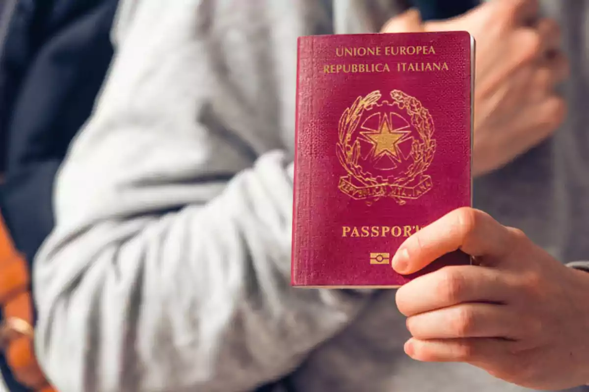 A person holding a red Italian passport. A person holding a red Italian passport.