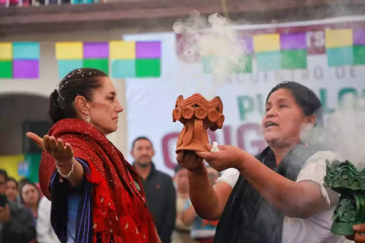 Dos mujeres participan en una ceremonia tradicional con incienso y vestimenta típica, rodeadas de personas y decoraciones coloridas.