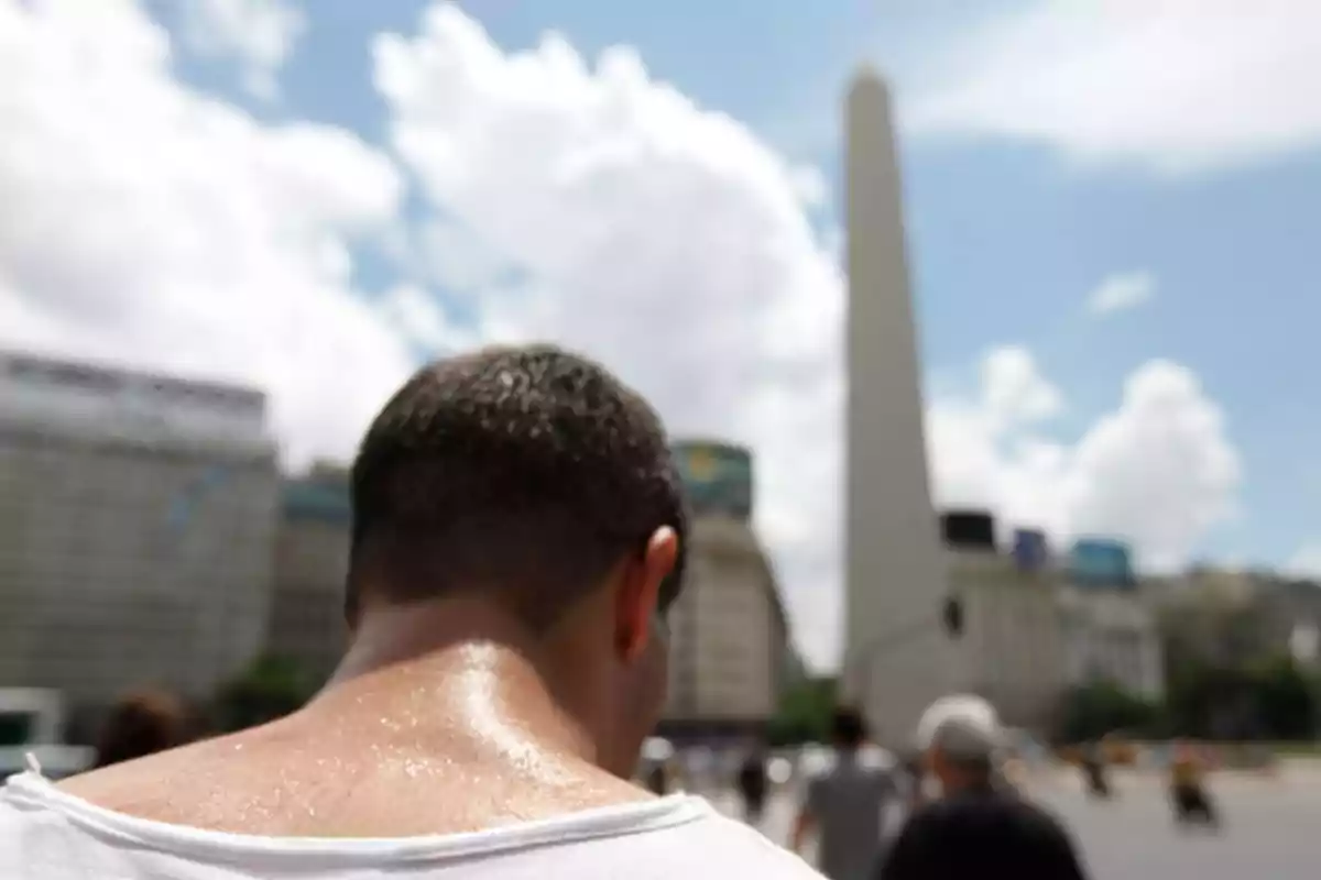 Persona de espaldas caminando hacia el Obelisco de Buenos Aires en un día soleado.