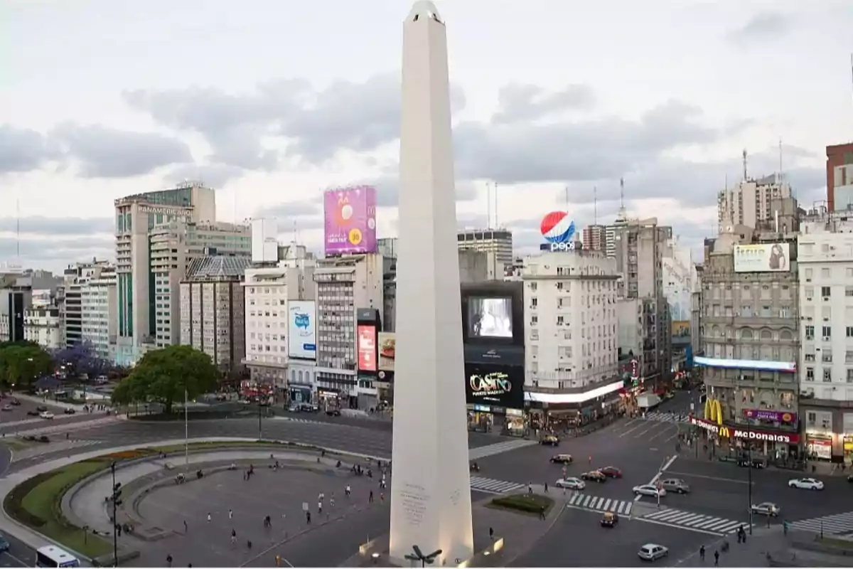 Vista del Obelisco en una intersección concurrida de la ciudad con edificios y carteles publicitarios alrededor.