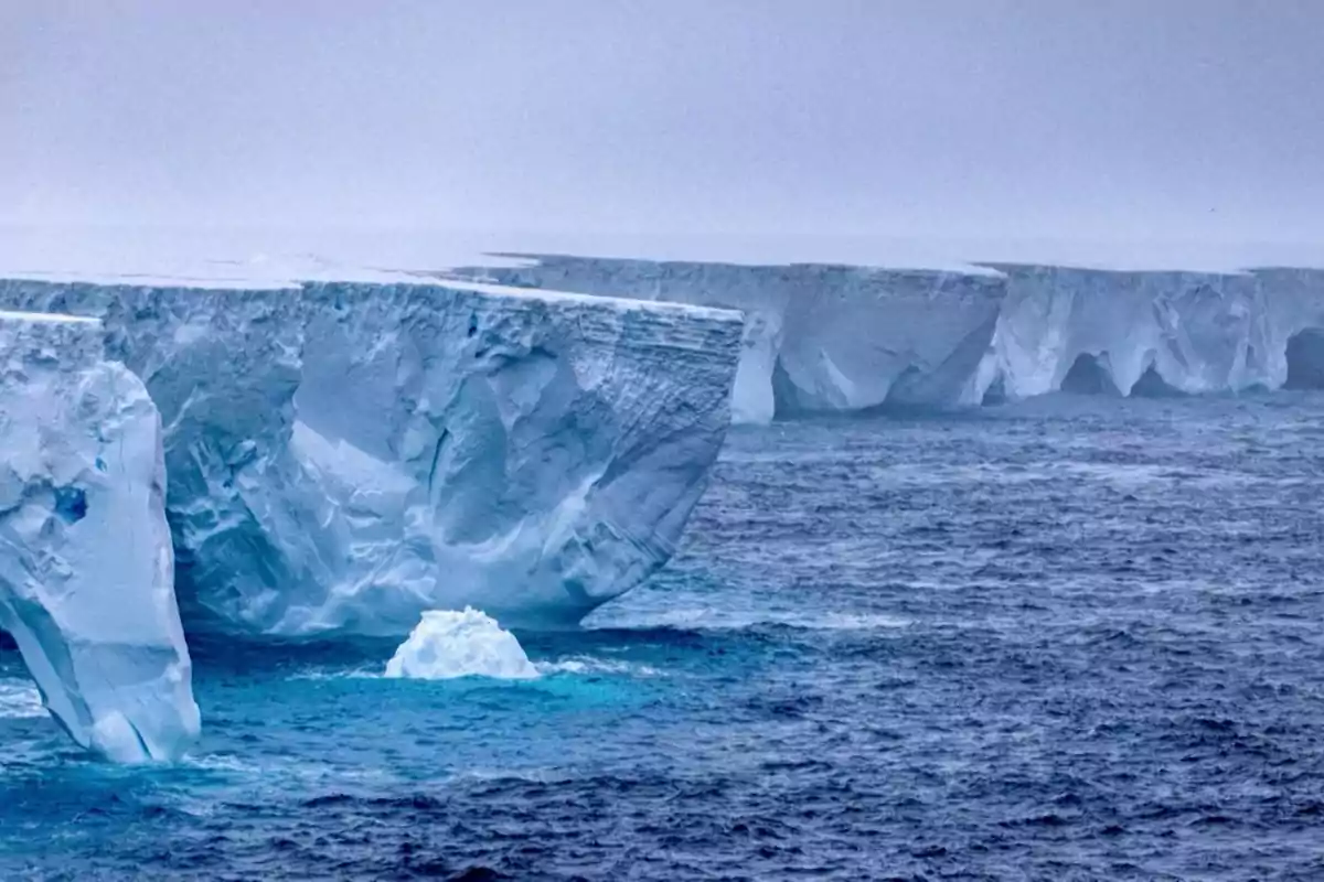 Un enorme iceberg flotando en un océano frío y nublado. Un enorme iceberg flotando en un océano frío y nublado.