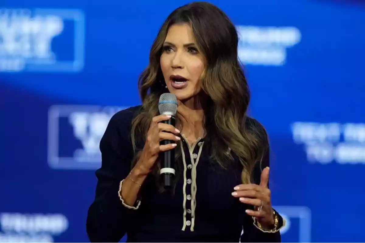 Woman speaking at an event with a microphone in hand and a blue background. Woman speaking at an event with a microphone in hand and a blue background.