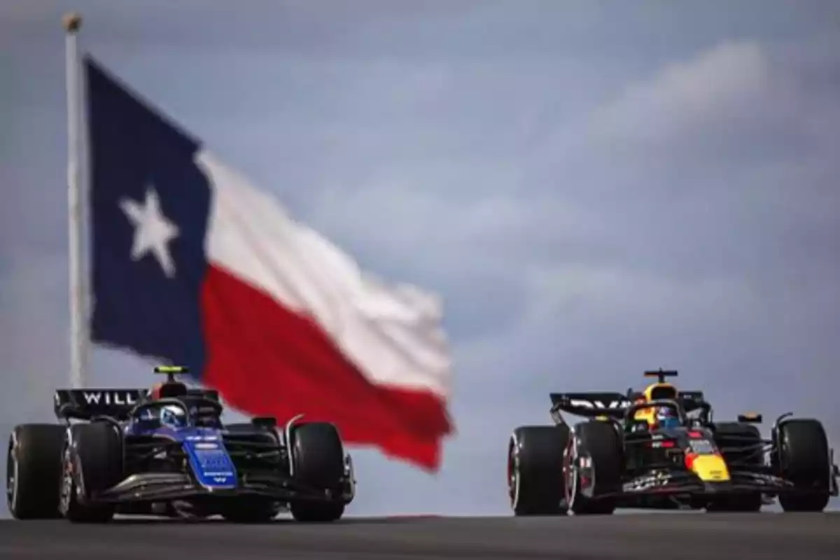 Dos autos de Fórmula 1 compiten en una pista con una gran bandera de Chile ondeando en el fondo.