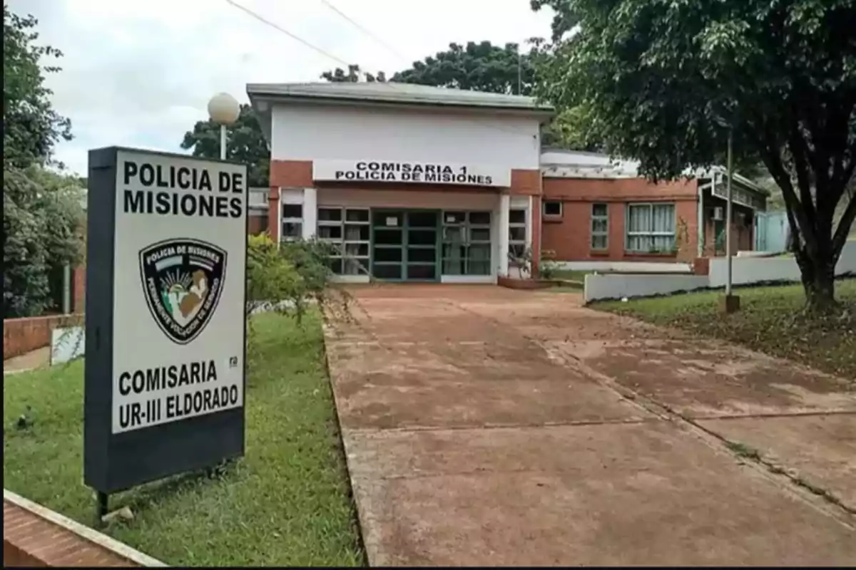 Edificio de la Comisaría 1 de la Policía de Misiones en Eldorado, rodeado de árboles y con un cartel al frente.