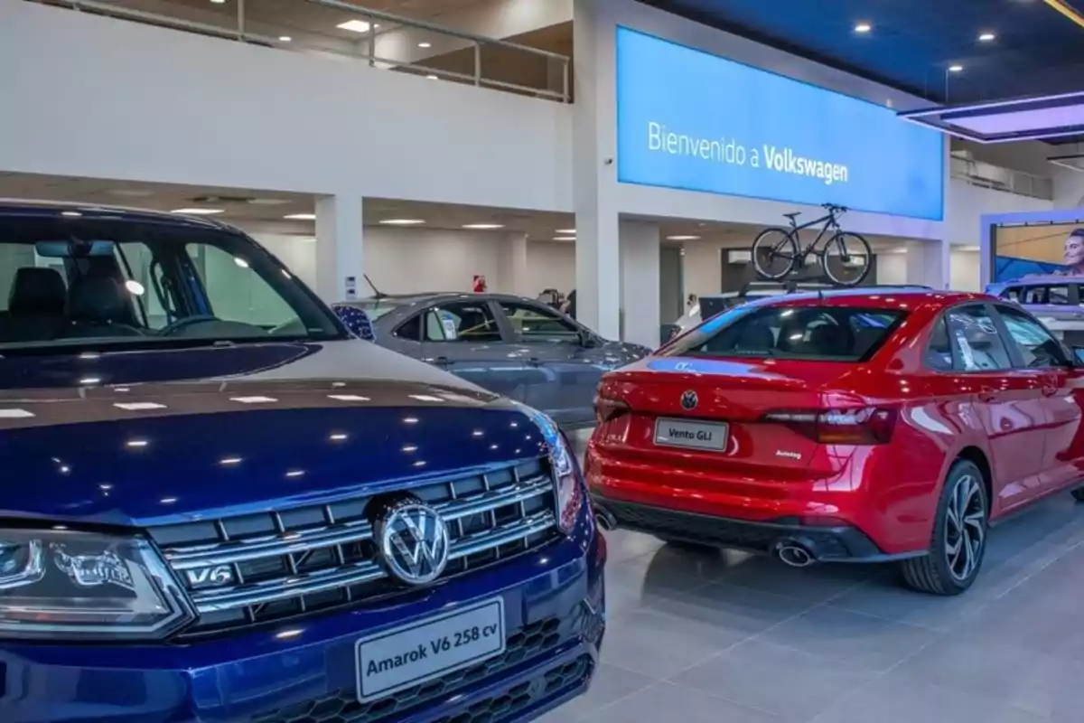 Exhibición de autos Volkswagen en un concesionario con un cartel de bienvenida en el fondo.