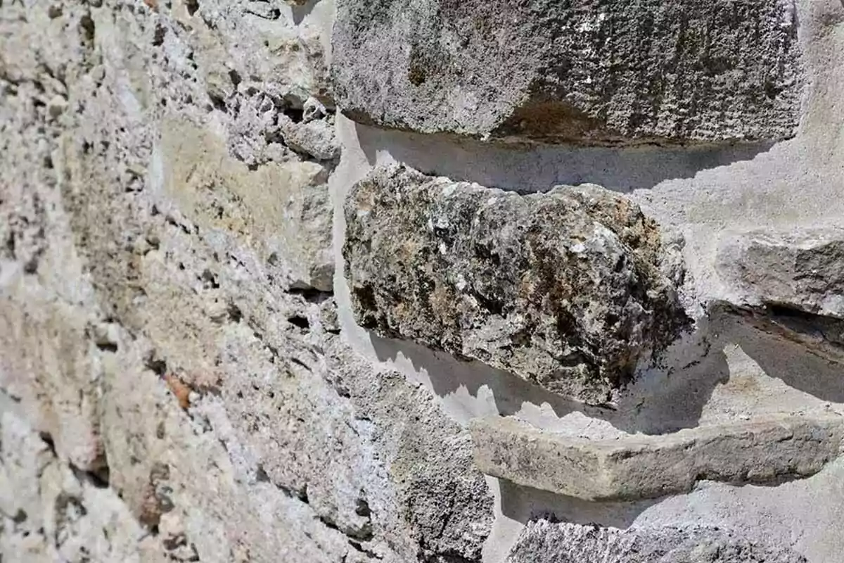 A stone wall with a rough texture and gray and brown tones. A stone wall with a rough texture and gray and brown tones.