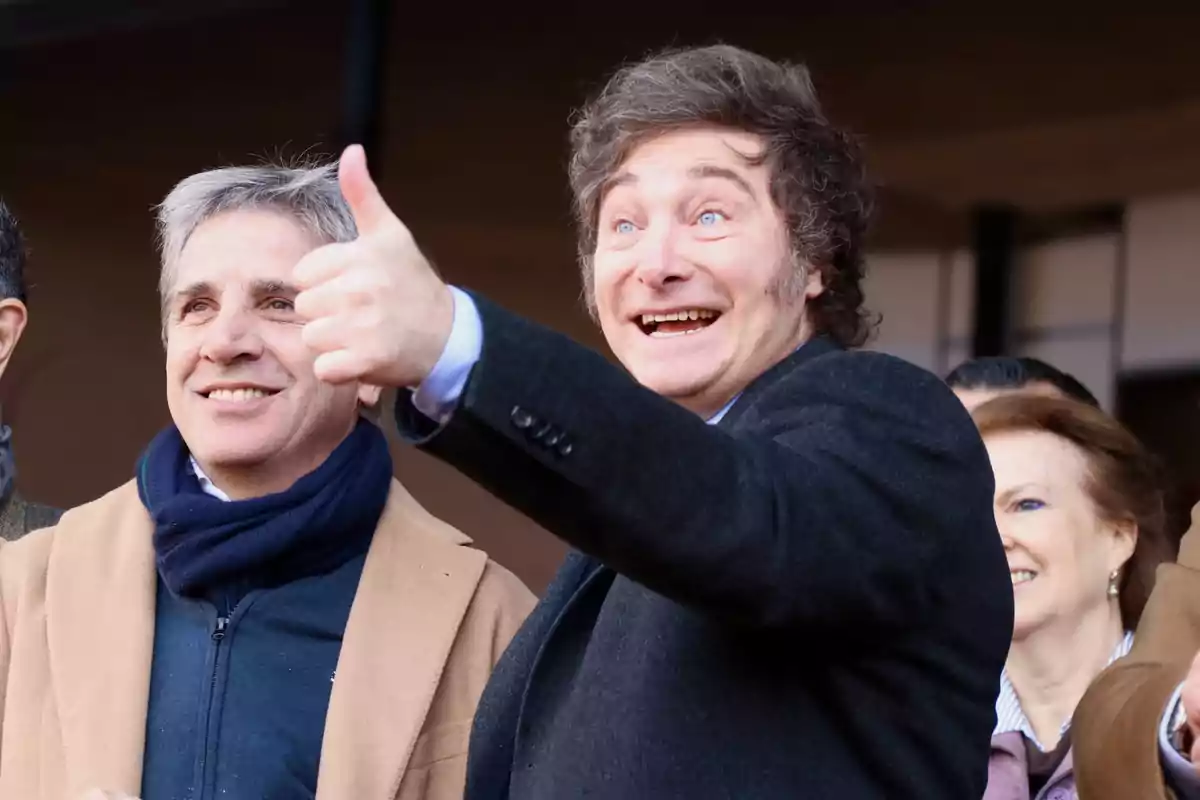 Hombre sonriente con el pulgar hacia arriba acompañado de otras personas en un evento al aire libre