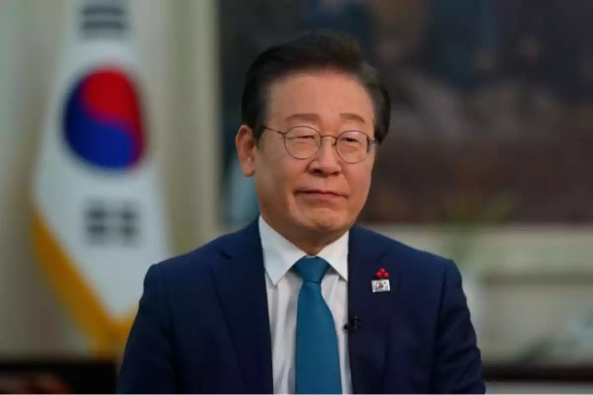 A man in glasses and a blue suit poses in front of a South Korean flag. A man in glasses and a blue suit poses in front of a South Korean flag.