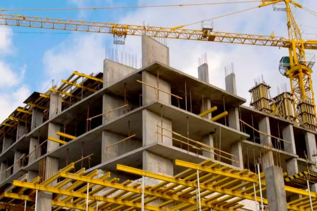 Edificio en construcción con estructura de concreto y grúas amarillas en el fondo Edificio en construcción con estructura de concreto y grúas amarillas en el fondo