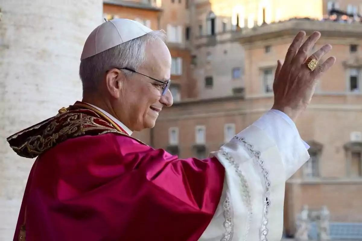 Hombre con vestimenta religiosa y solideo blanco saludando con la mano levantada frente a un edificio histórico Hombre con vestimenta religiosa y solideo blanco saludando con la mano levantada frente a un edificio histórico