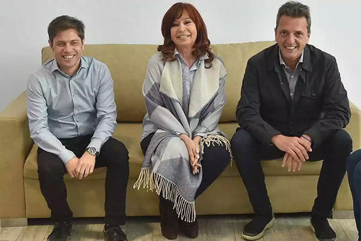 Tres personas sentadas en un sofá, sonriendo hacia la cámara.