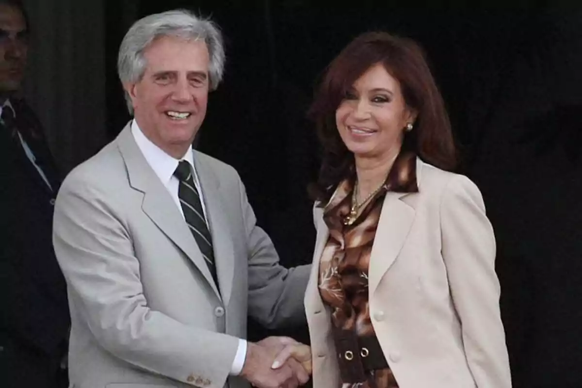 Two elegantly dressed people shake hands and smile in front of the camera. Two elegantly dressed people shake hands and smile in front of the camera.