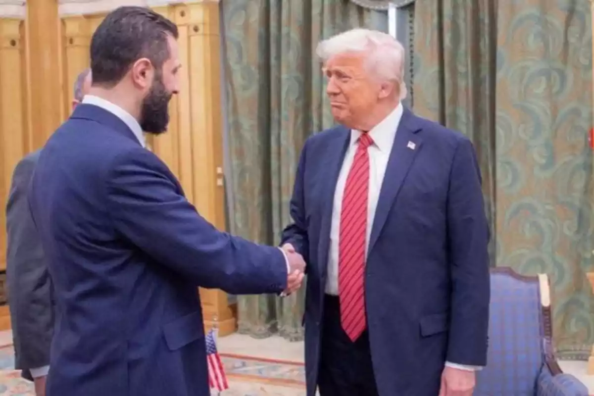 Dos hombres de traje estrechándose la mano en una sala con cortinas y muebles elegantes. Dos hombres de traje estrechándose la mano en una sala con cortinas y muebles elegantes.