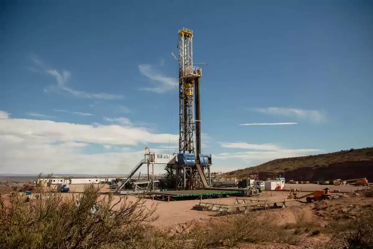 Drilling rig in an oil field under a clear sky.