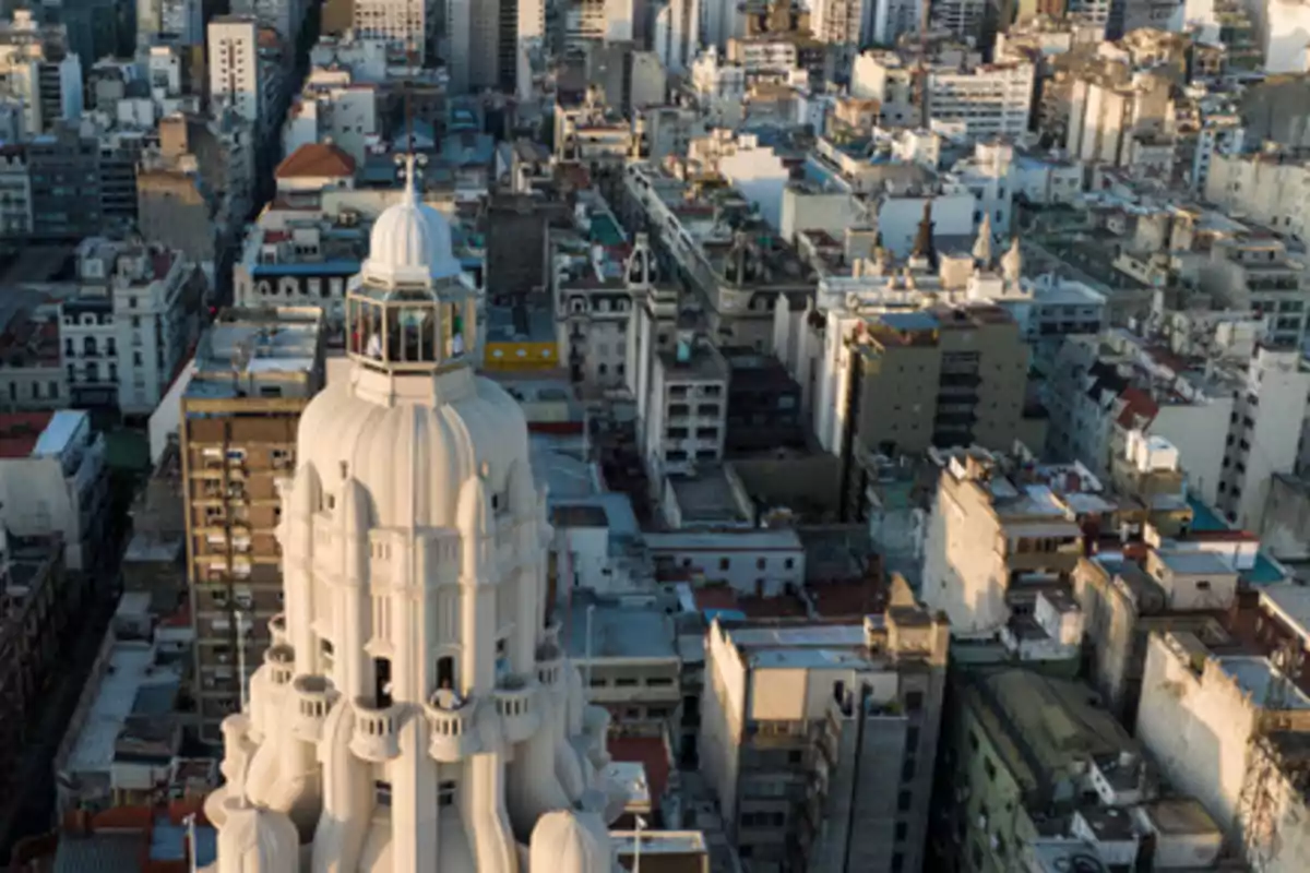 Vista aérea de una ciudad con un edificio blanco destacado en primer plano y numerosos edificios alrededor.