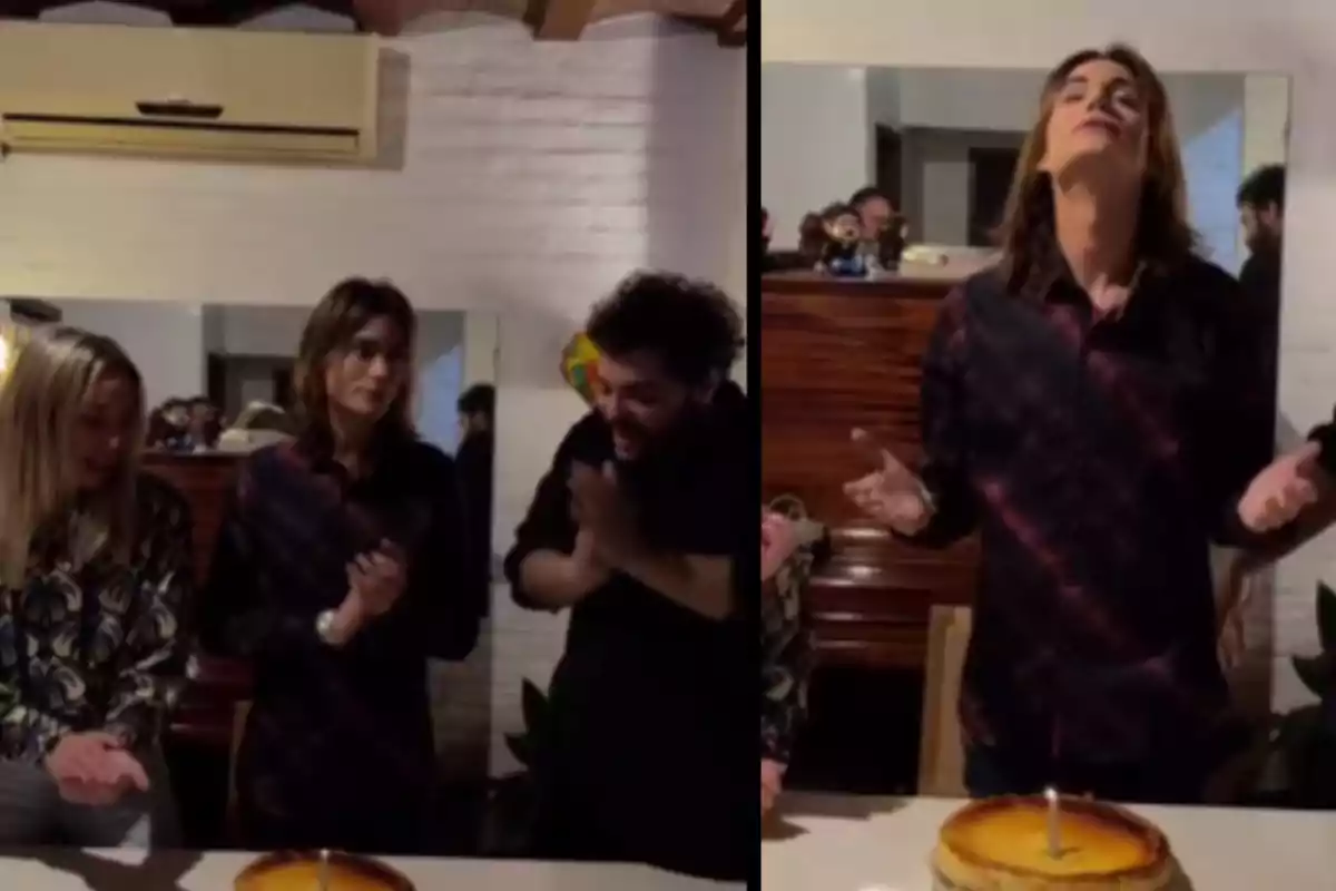 Un grupo de personas está reunido alrededor de una mesa con un pastel que tiene una vela encendida, una persona parece estar haciendo un deseo mientras las otras observan y aplauden. Un grupo de personas está reunido alrededor de una mesa con un pastel que tiene una vela encendida, una persona parece estar haciendo un deseo mientras las otras observan y aplauden.