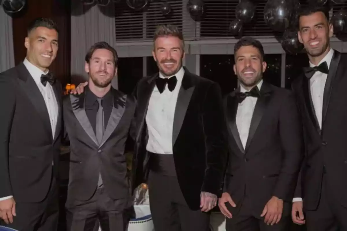 Five men dressed in suits pose together at a fancy event. Five men dressed in suits pose together at a fancy event.