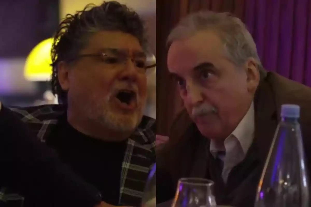 Two men in a restaurant, one seems to be speaking energetically while the other watches him alertly.