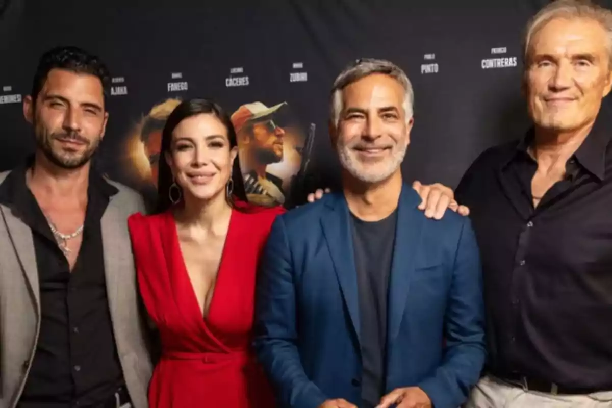 A group of four people posing together in front of a dark background with movie posters. A group of four people posing together in front of a dark background with movie posters.