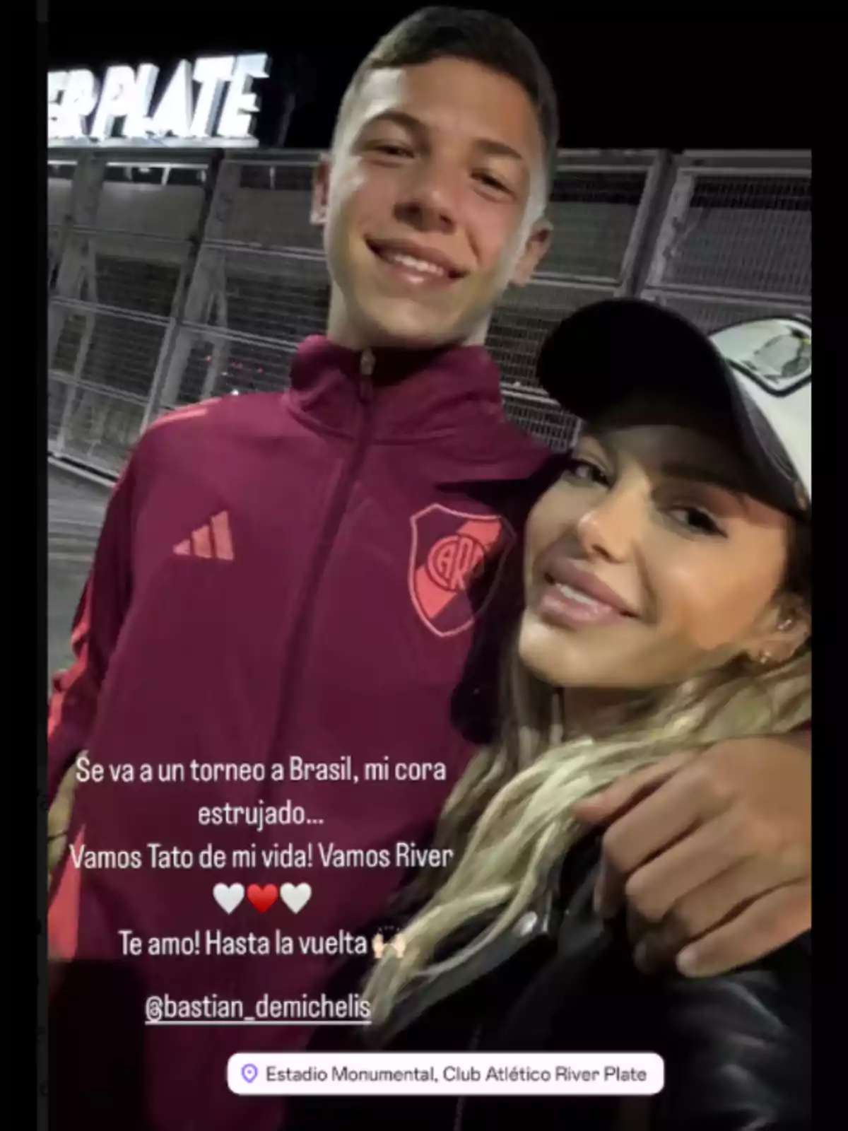 Una mujer y un joven sonríen mientras se toman una selfie frente a una estructura con el logo de River Plate. El joven lleva una chaqueta deportiva del equipo. Una mujer y un joven sonríen mientras se toman una selfie frente a una estructura con el logo de River Plate. El joven lleva una chaqueta deportiva del equipo.