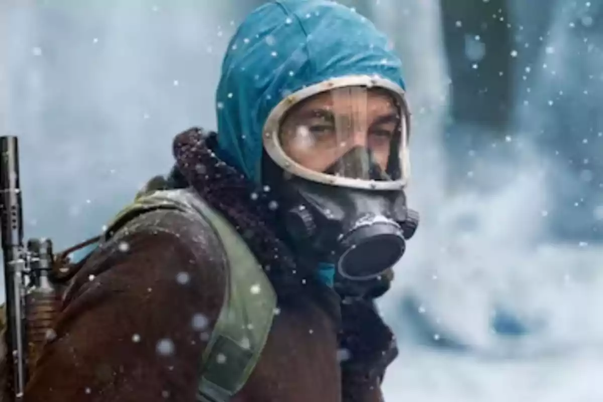 Un hombre con máscara de gas y capucha azul en un entorno nevado. Un hombre con máscara de gas y capucha azul en un entorno nevado.