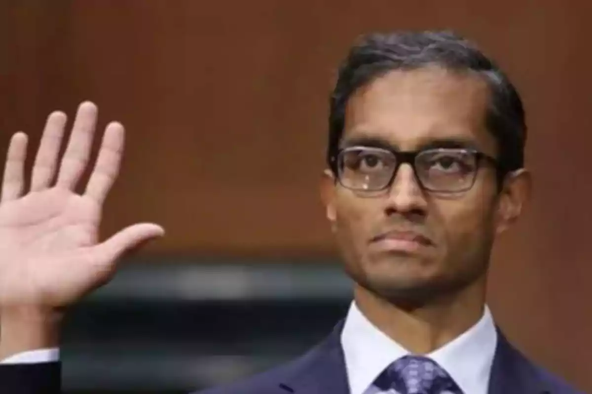 Un hombre con gafas levanta la mano en un gesto solemne. Un hombre con gafas levanta la mano en un gesto solemne.