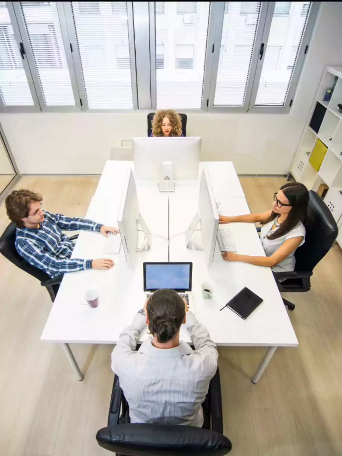 Personas trabajando en una oficina moderna con escritorios blancos y computadoras. Personas trabajando en una oficina moderna con escritorios blancos y computadoras.