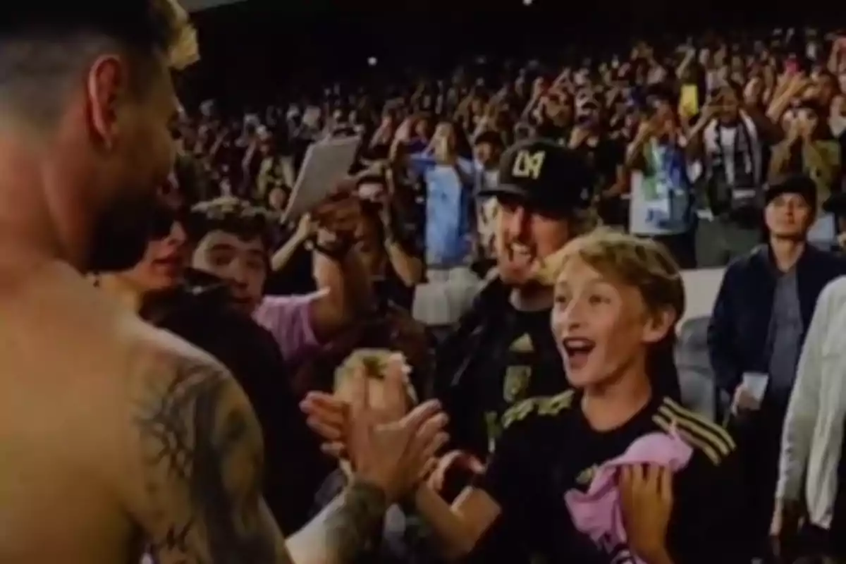An excited boy high-fives a player in a stadium full of fans. An excited boy high-fives a player in a stadium full of fans.