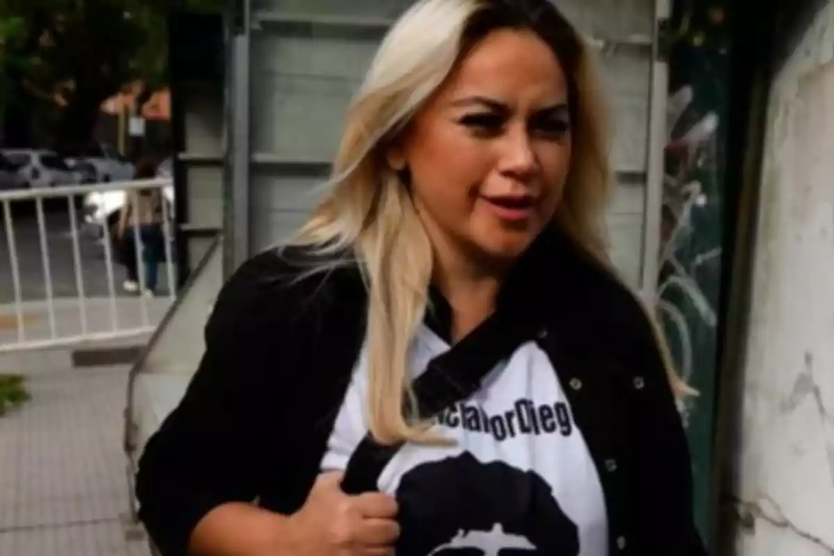 Mujer de cabello rubio largo caminando por la calle con una camiseta blanca y chaqueta negra Mujer de cabello rubio largo caminando por la calle con una camiseta blanca y chaqueta negra