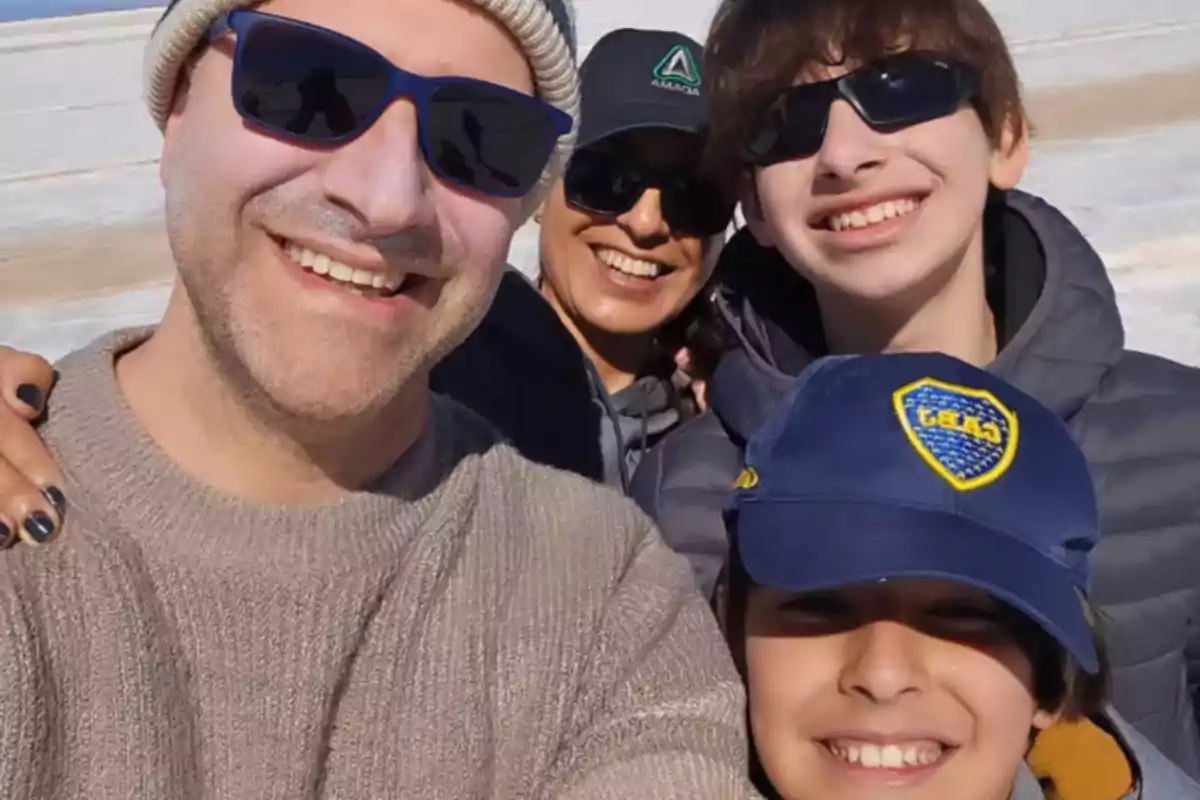 Family smiling and posing for a selfie outdoors on a sunny day