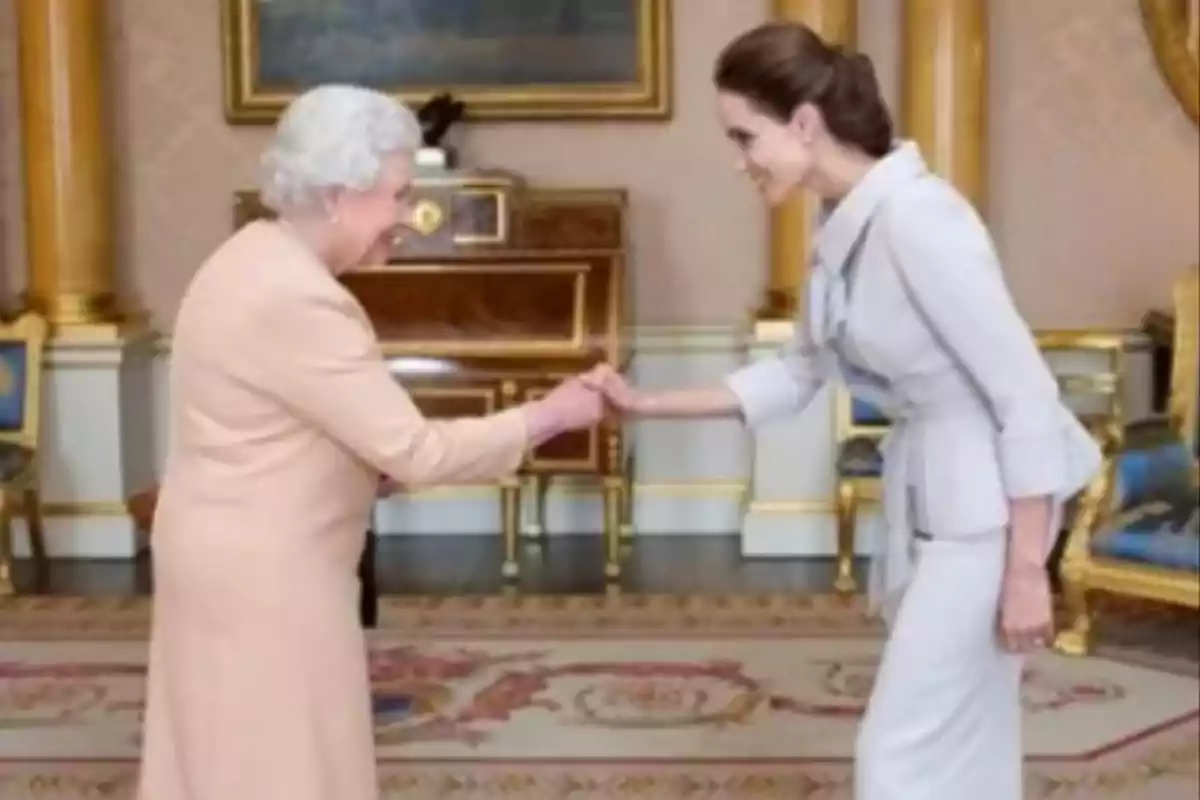 Dos mujeres elegantemente vestidas se saludan con un apretón de manos en una lujosa sala decorada con muebles clásicos y alfombra ornamental Dos mujeres elegantemente vestidas se saludan con un apretón de manos en una lujosa sala decorada con muebles clásicos y alfombra ornamental