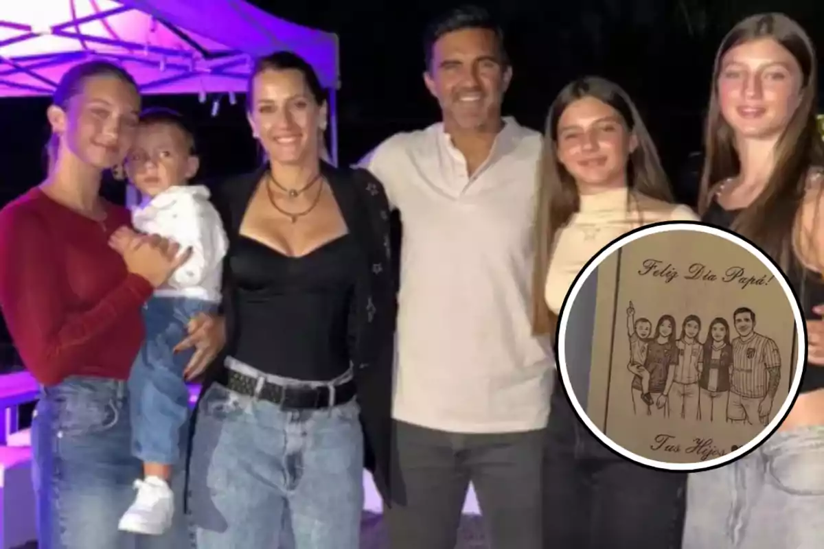 Familia posando junta y sonriente con un dibujo enmarcado que los representa y un mensaje de felicitación para el papá