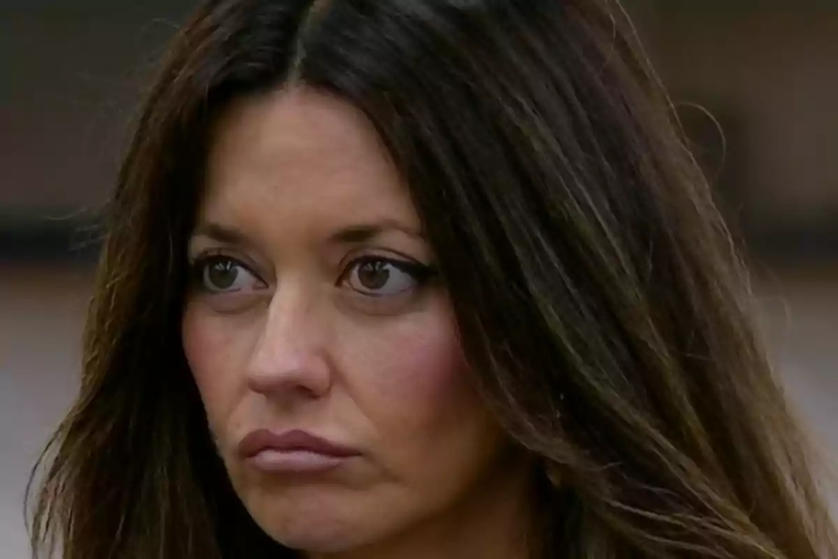 Mujer de cabello largo y oscuro con expresión seria y labios fruncidos Mujer de cabello largo y oscuro con expresión seria y labios fruncidos
