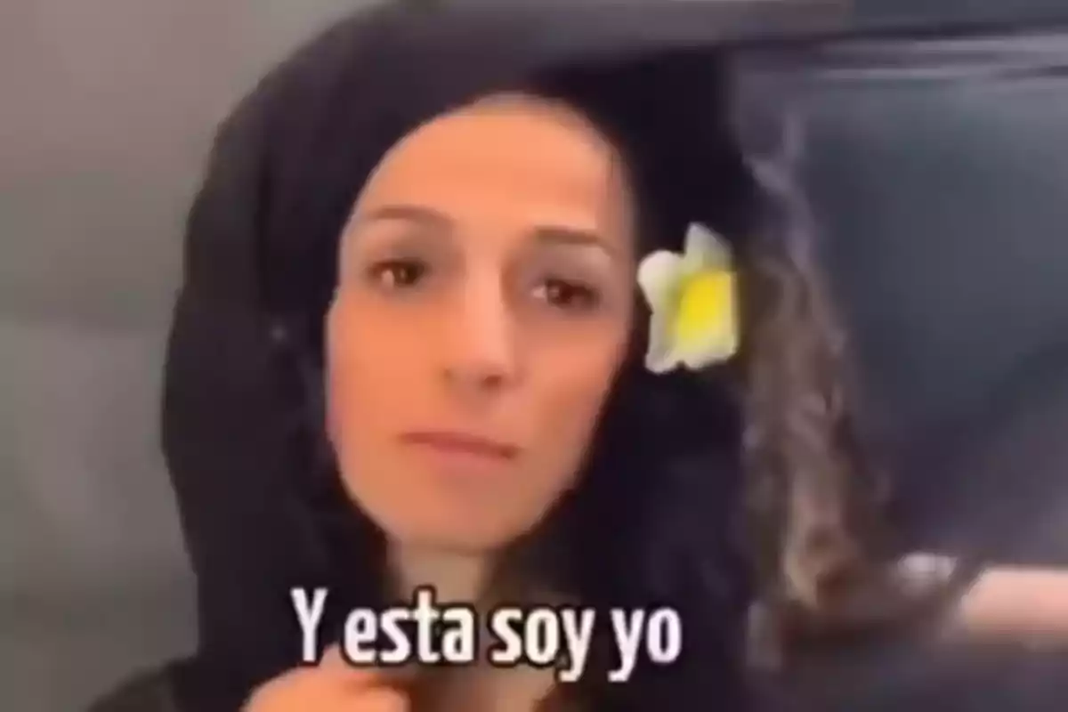 Mujer con cabello rizado y una flor blanca en el pelo mirando a la cámara con la frase Y esta soy yo en la parte inferior Mujer con cabello rizado y una flor blanca en el pelo mirando a la cámara con la frase Y esta soy yo en la parte inferior