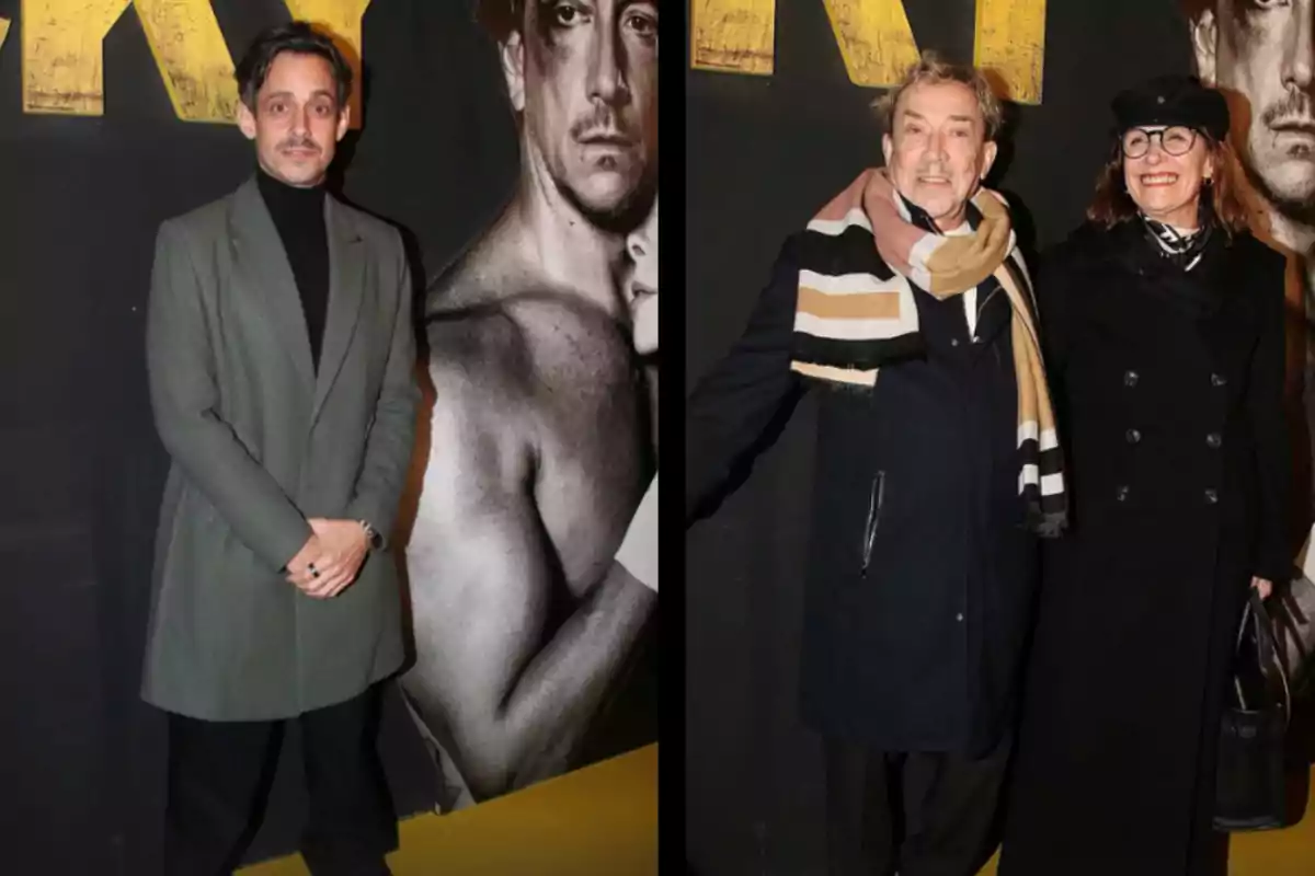 Three people pose at an event in front of a black backdrop with yellow letters and a black-and-white image of a muscular man. Three people pose at an event in front of a black backdrop with yellow letters and a black-and-white image of a muscular man.