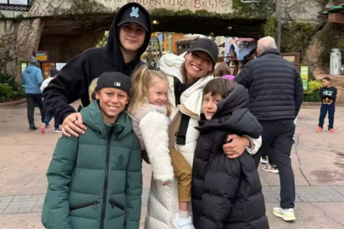 A group of warmly dressed people happily posing in a theme park.