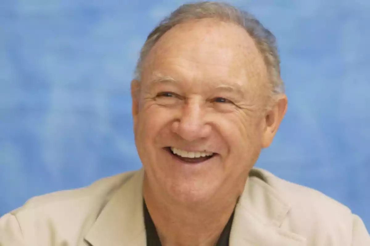 Un hombre mayor sonriendo con fondo azul.