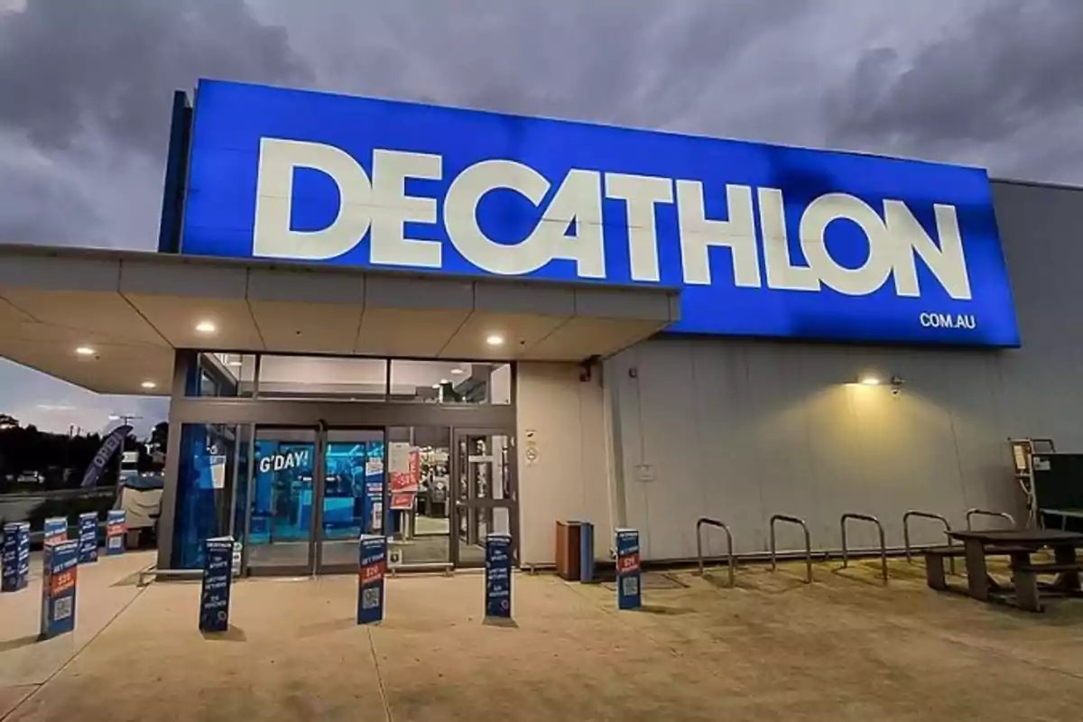 Entrada de una tienda Decathlon con un cartel luminoso azul y blanco.