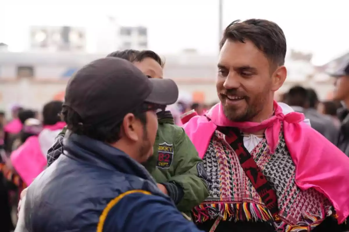 Un grupo de personas vestidas con ropa colorida interactúa en un evento al aire libre.