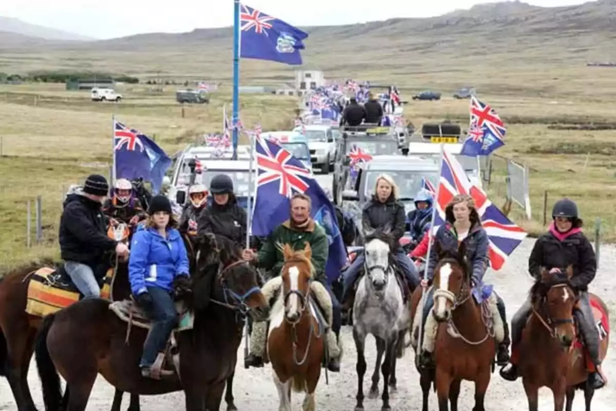 People riding horses and vehicles in a caravan carrying United Kingdom flags in a rural landscape People riding horses and vehicles in a caravan carrying United Kingdom flags in a rural landscape