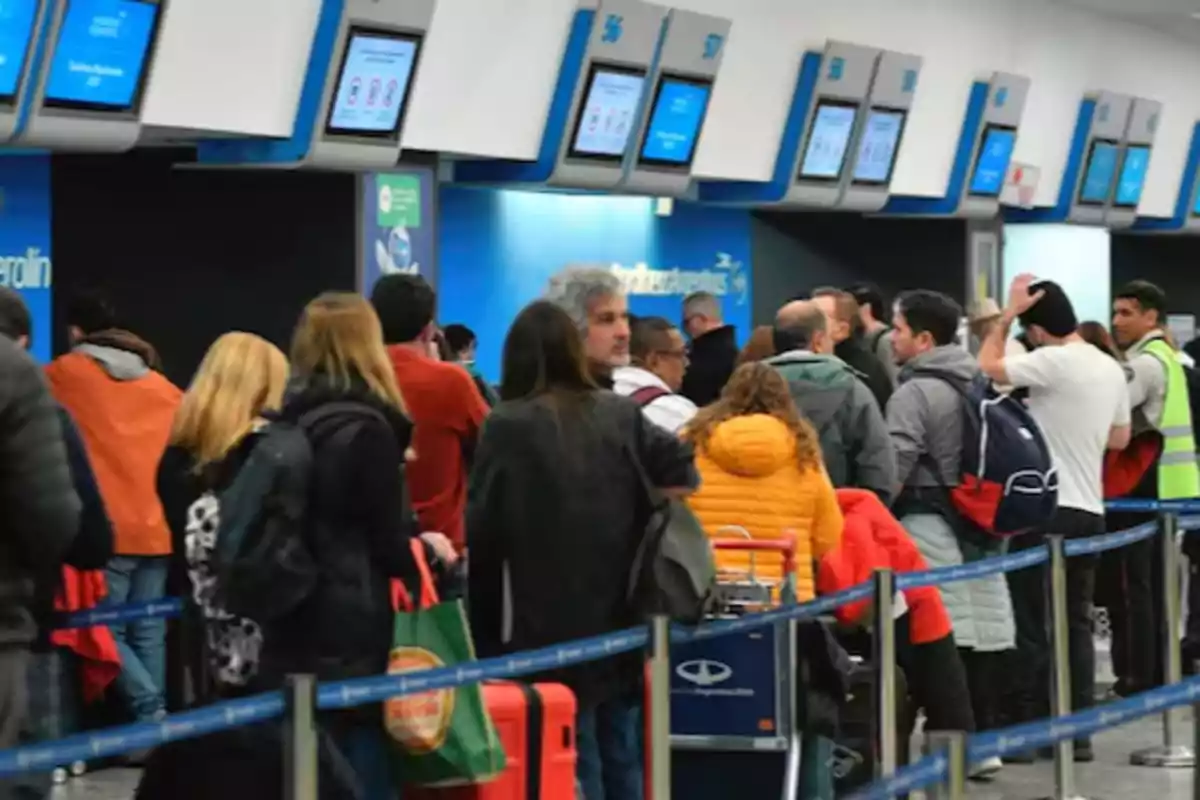 Personas haciendo fila en un mostrador de check-in en un aeropuerto.