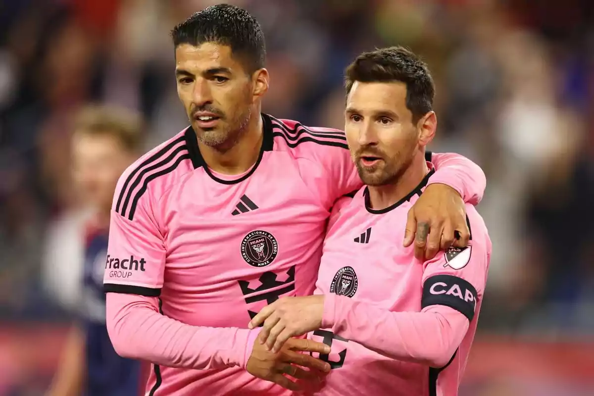 Dos jugadores de fútbol con uniforme rosa del equipo Inter Miami en el campo de juego.