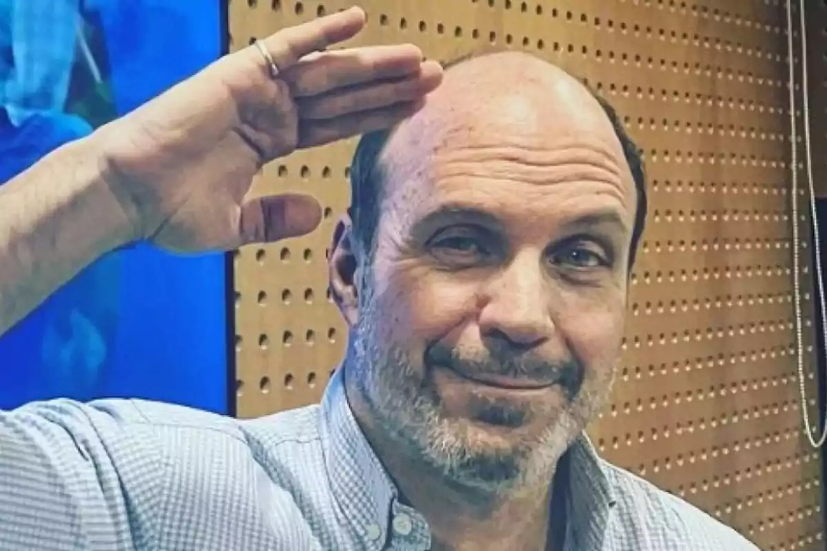 Hombre con camisa a cuadros haciendo un gesto de saludo con la mano en la frente.