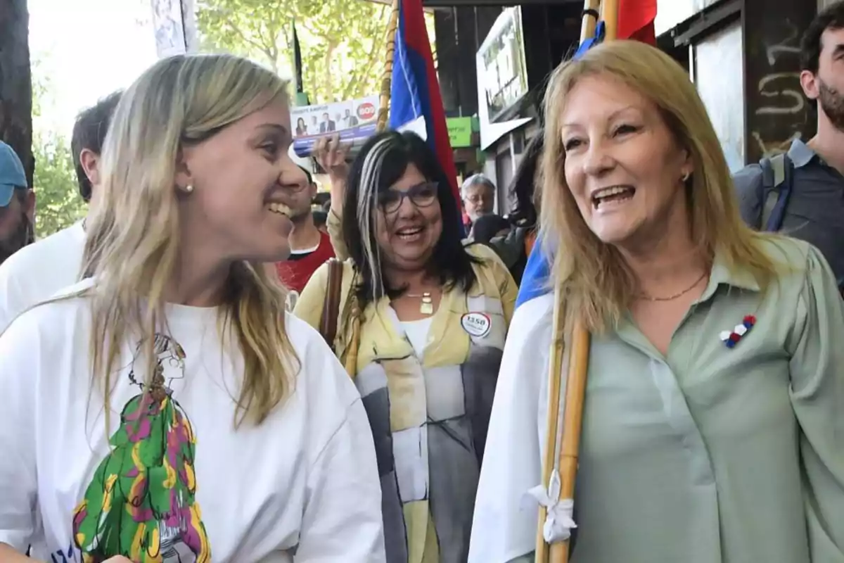 Un grupo de personas sonríe mientras camina al aire libre en un evento con banderas.