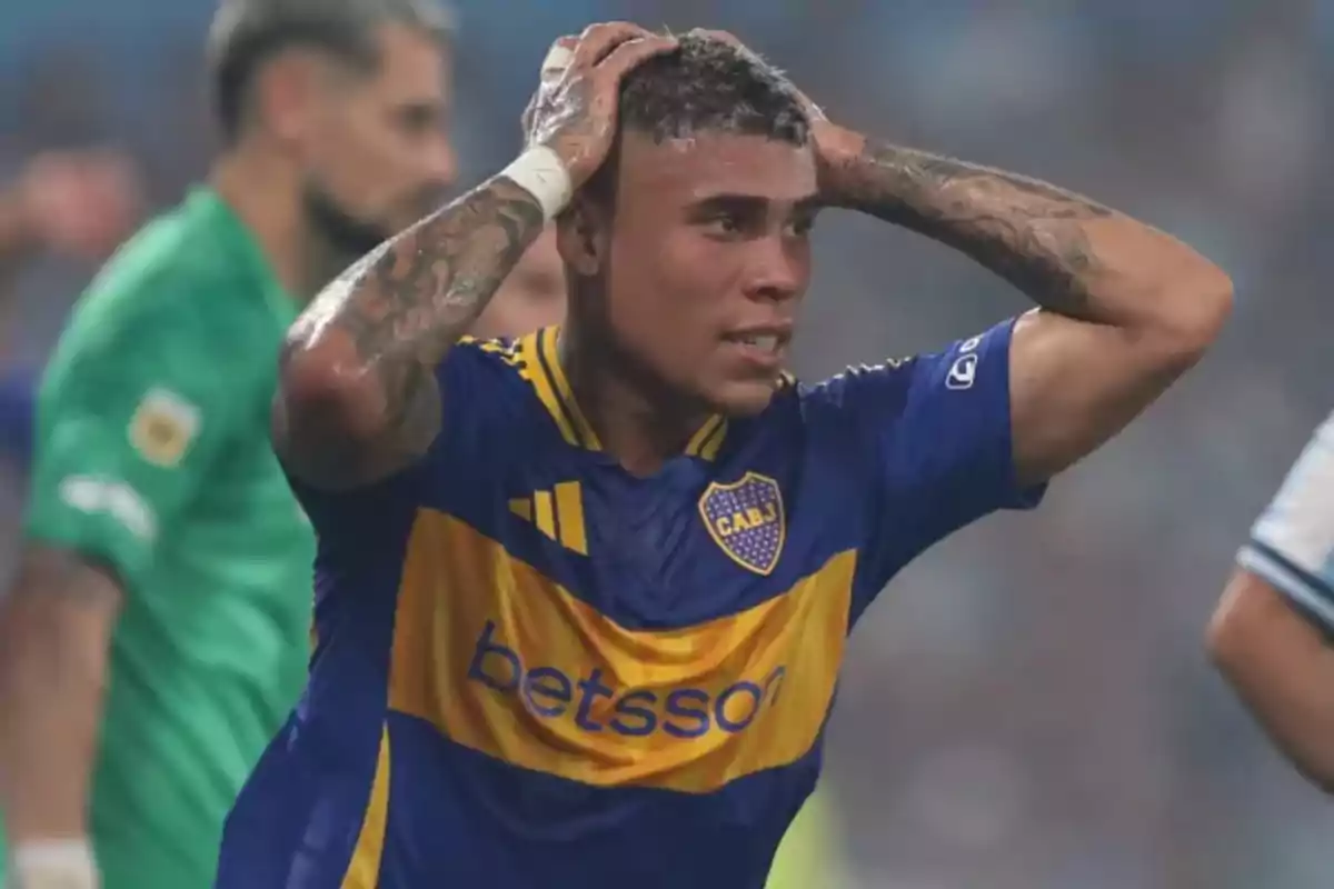Boca Juniors player with a frustrated expression holding his head in his hands during a match