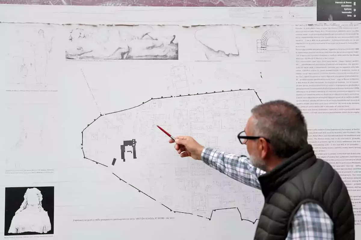 Un hombre con gafas y chaleco señala un plano arquitectónico grande con un bolígrafo rojo. Un hombre con gafas y chaleco señala un plano arquitectónico grande con un bolígrafo rojo.