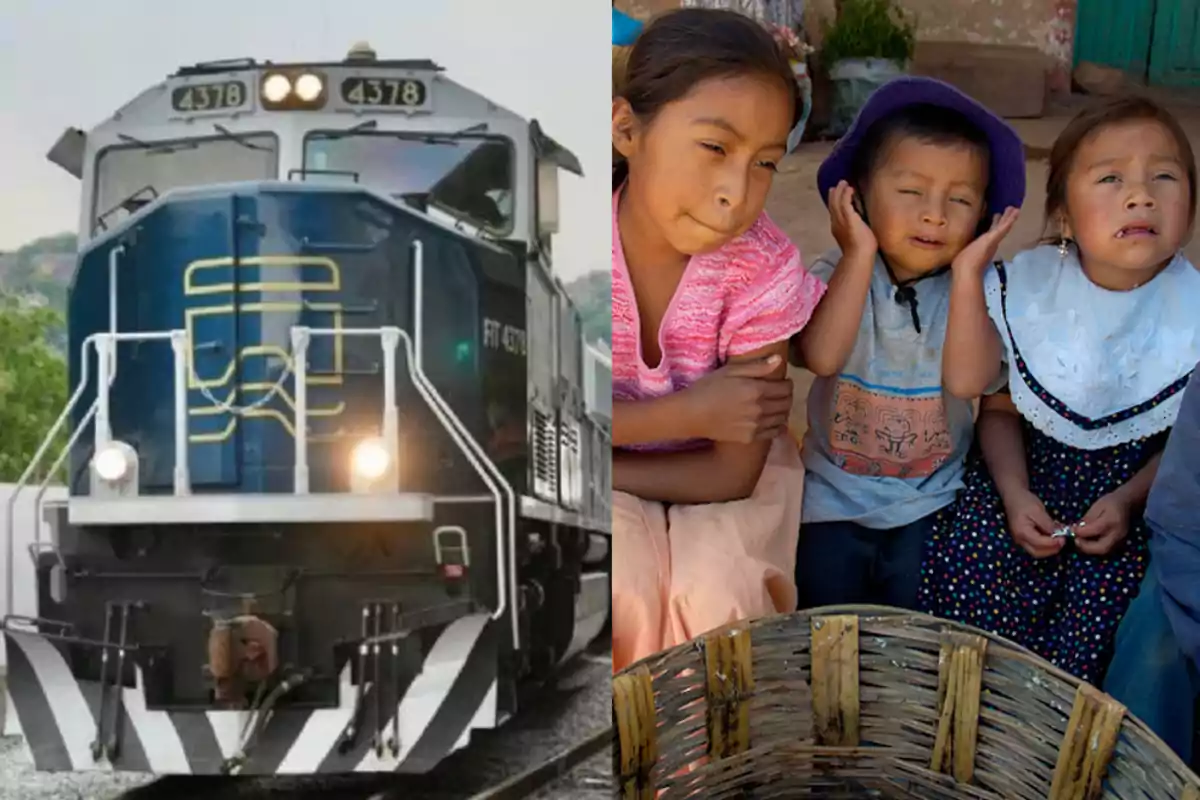 A blue train moves along the tracks while three small children, two girls and a boy, sit together; the boy covers his ears and the girls look uncomfortable.