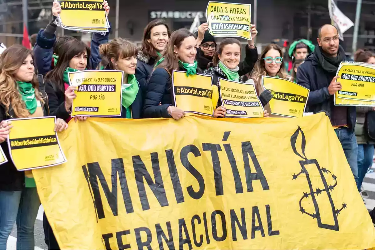 Group of people showing in favor of legal abortion in Argentina, holding yellow Amnesty International signs and green scarves Group of people showing in favor of legal abortion in Argentina, holding yellow Amnesty International signs and green scarves